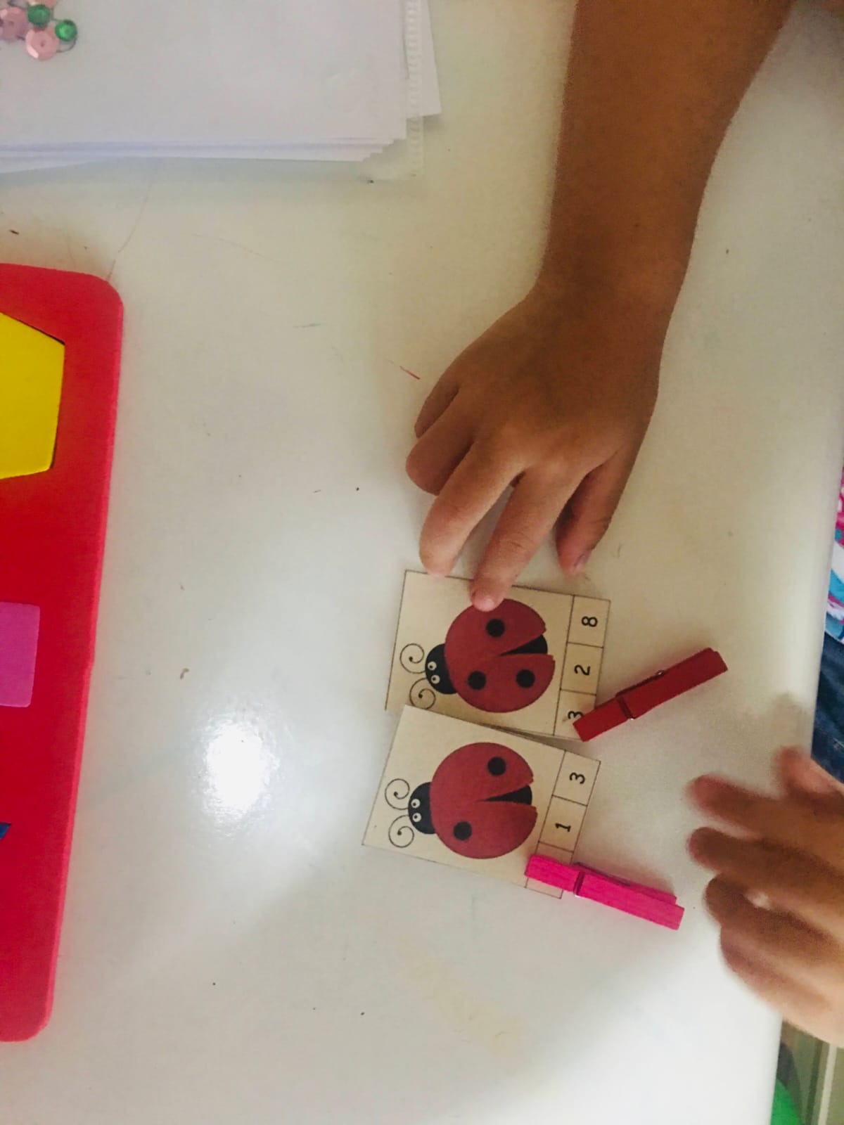 Criança contando as pintas de joaninhas em uma atividade com prendedores