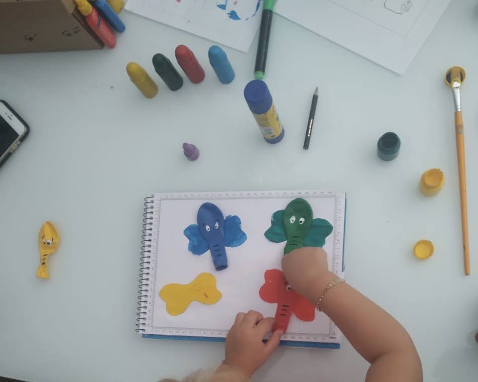Criança realizando uma atividade artística com elefantes coloridos